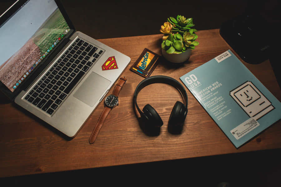 Red And Black Headphones Resting Atop A Silver Laptop. Wallpaper