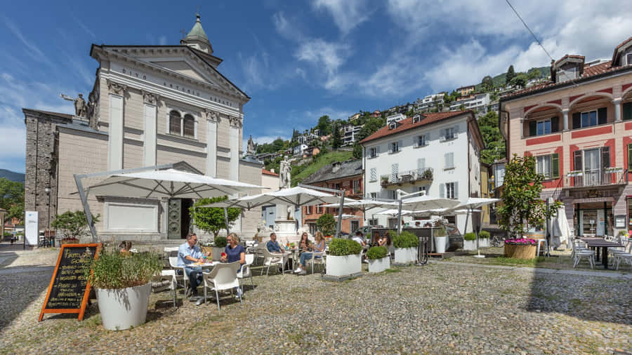 Scenic View Of A Picturesque Town Locarno Nestling By The Lake Against The Backdrop Of Majestic Mountains. Wallpaper