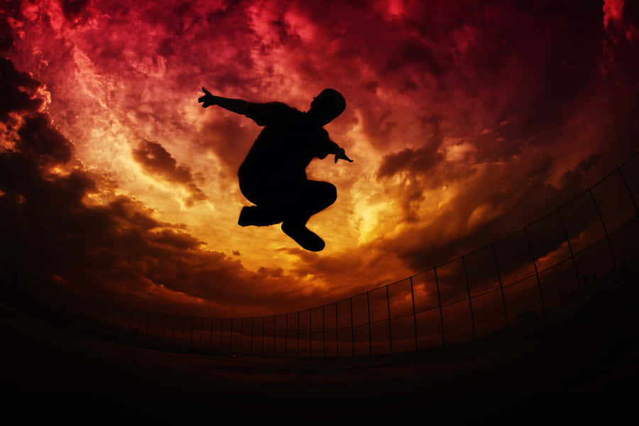 Silhouette Jump Against Sunset Sky Wallpaper