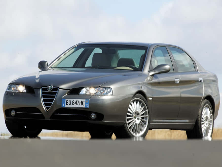 Sleek Alfa Romeo 156 Driving On An Open Road Wallpaper