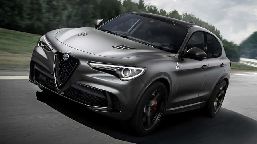 Sleek Alfa Romeo Stelvio On Picturesque Mountain Road Wallpaper