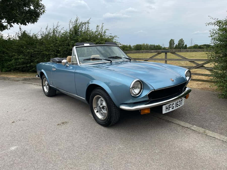 Sleek Fiat 124 Spider Cruising The Open Road Wallpaper