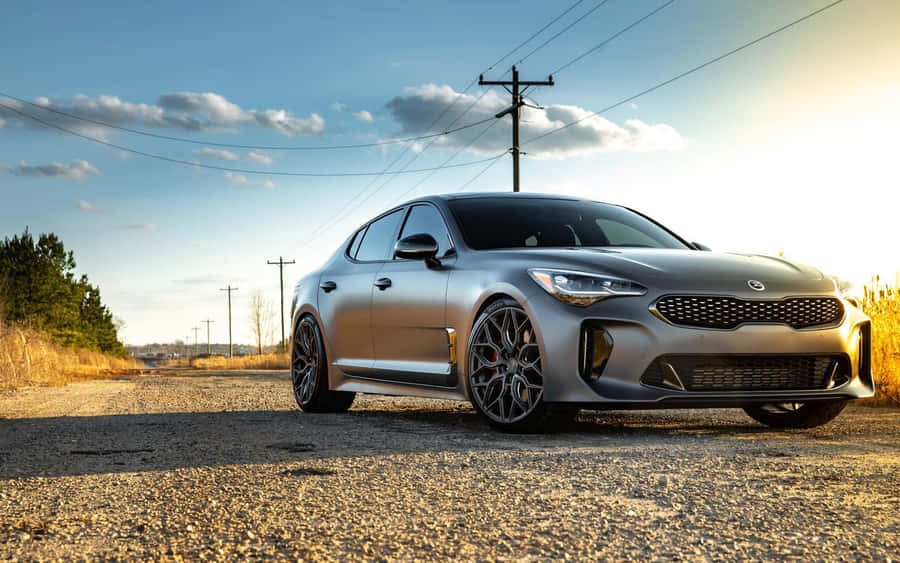 Sleek Kia Stinger Sports Sedan Parked On A Scenic Road Wallpaper