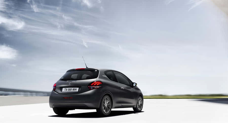 Sleek Peugeot 208 Gliding Effortlessly On A Winding Road Wallpaper