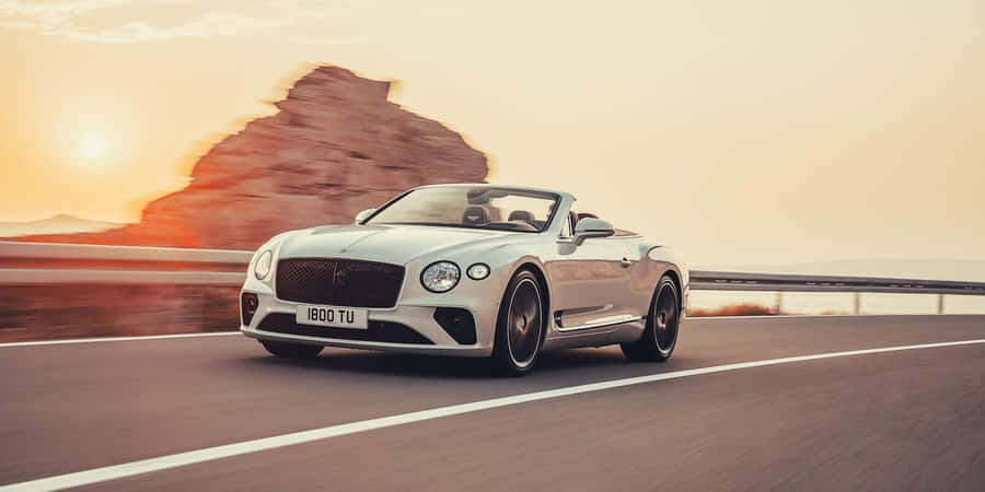 Sleek Silver Convertible Cruising On The Highway Wallpaper