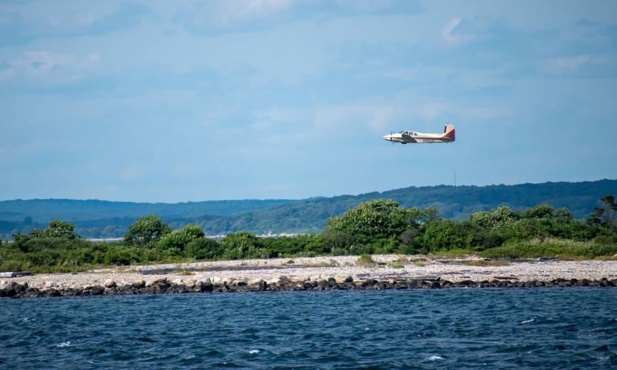 Small Plane Flying Over Ocean Wallpaper