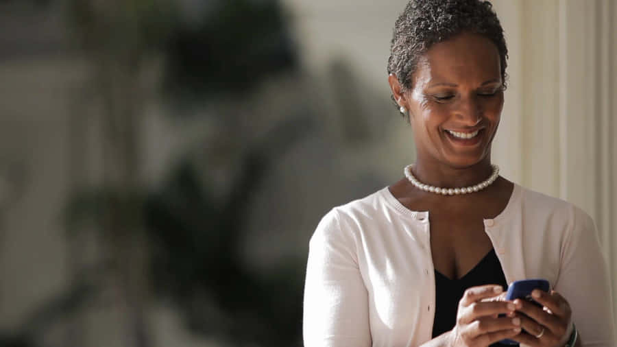 Smiling Middle Aged Woman Using Smartphone.jpg Wallpaper