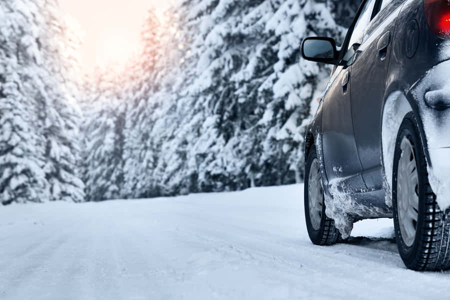 Snowy Winter Road With A Vehicle Driving In Challenging Conditions Wallpaper