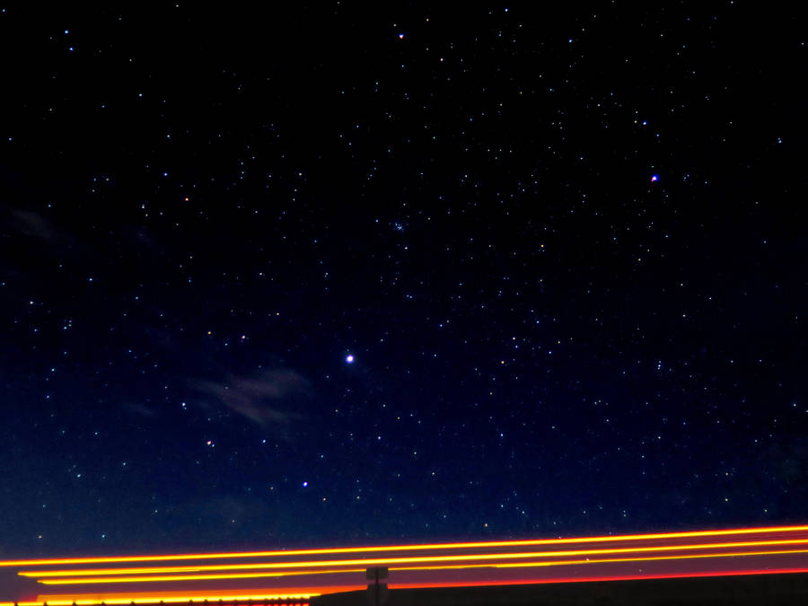 Streaks Of Light Under A Starry Night Wallpaper