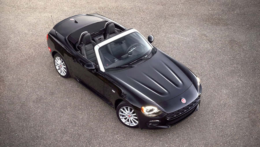 Stunning Fiat 124 Spider Cruising On Scenic Road Wallpaper