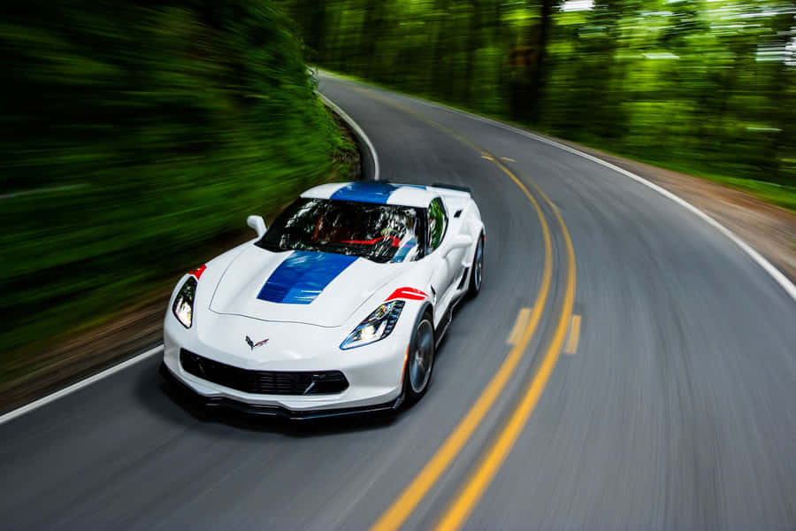 Stunning White Chevrolet Corvette Grand Sport Cruising On The Road Wallpaper