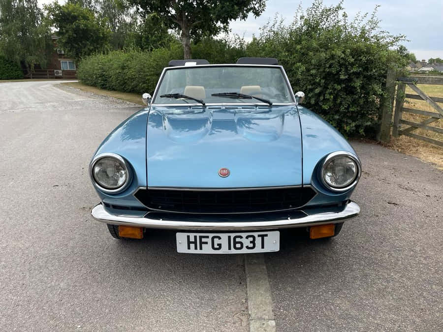 Stylish Fiat 124 Spider Cruising On The Road Wallpaper