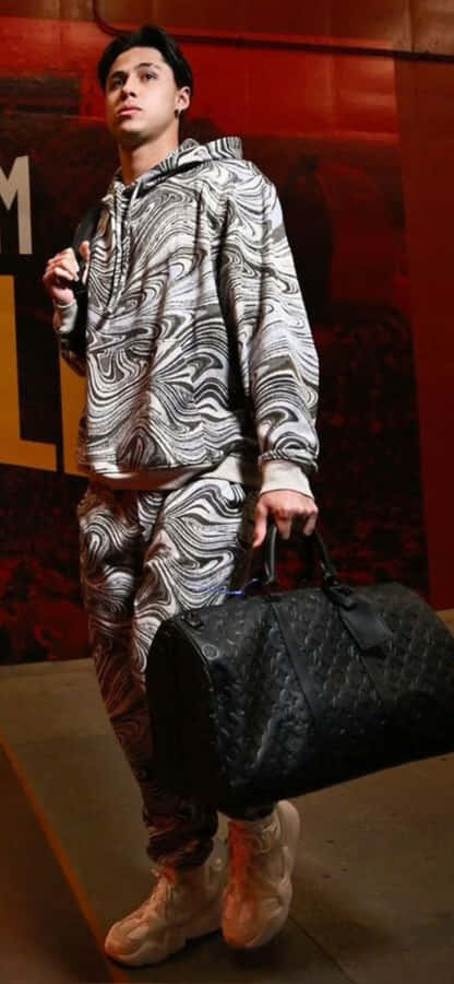 Stylish Manwith Patterned Outfitand Duffle Bag Wallpaper