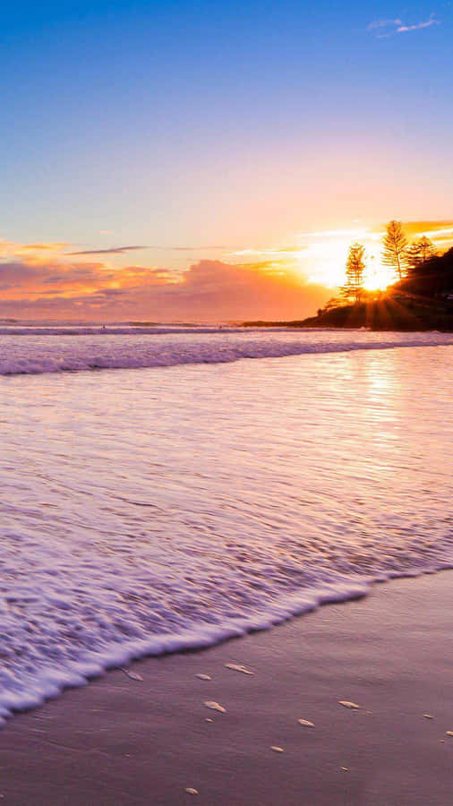 Take In The Beauty Of The Setting Sun On A Pristine Beach. Wallpaper