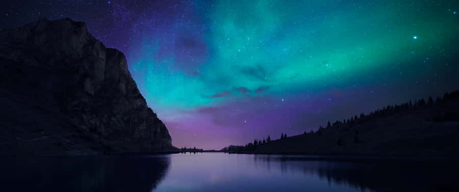 The Aurora Borealis Is Seen Over A Lake Wallpaper