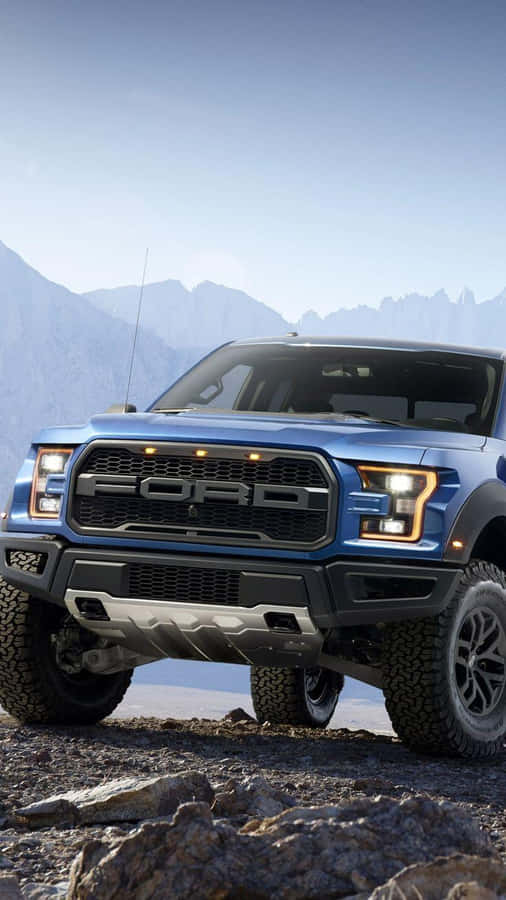 The Blue Ford F - 150 Raptor Is Parked On A Rocky Mountain Wallpaper
