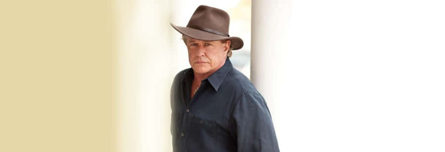 Tom Berenger Striking A Powerful Pose Against A Captivating Background Wallpaper