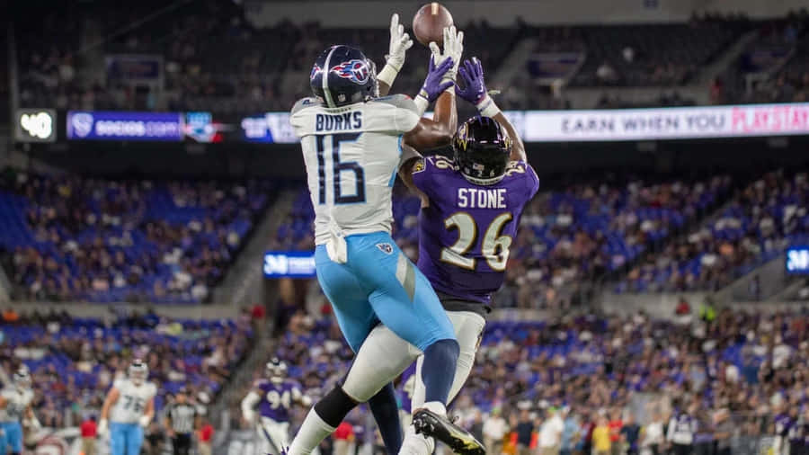 Treylon Burks Catching Football Against Defender Wallpaper