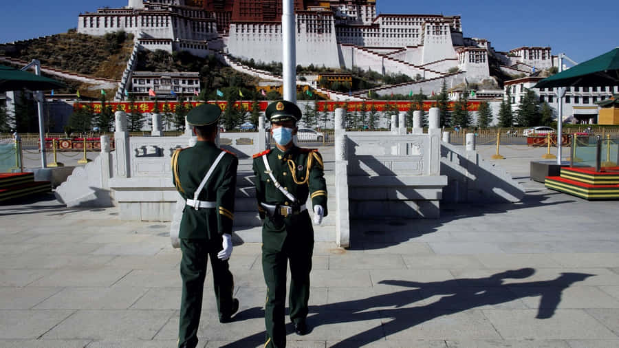 Two Men In Front Of Potala Palace In Lhasa Wallpaper