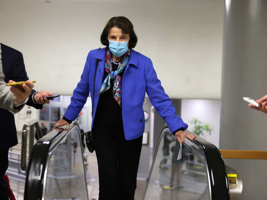 U.s. Senator Dianne Feinstein Wearing A Mask On An Escalator Wallpaper
