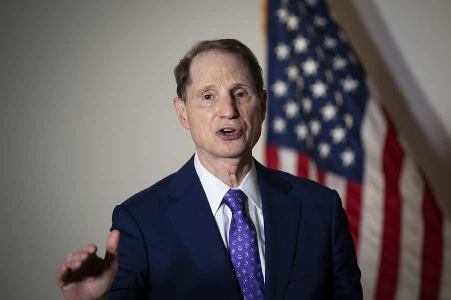 Us Senator Ron Wyden Standing Proud In Front Of The Us Flag Wallpaper