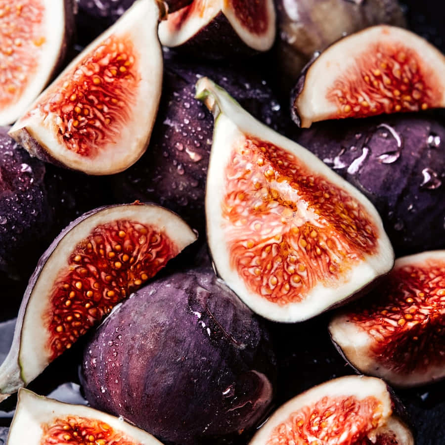 Vibrant Purple Figs Camouflaged Against A Backdrop Of Dark Foliage. Wallpaper