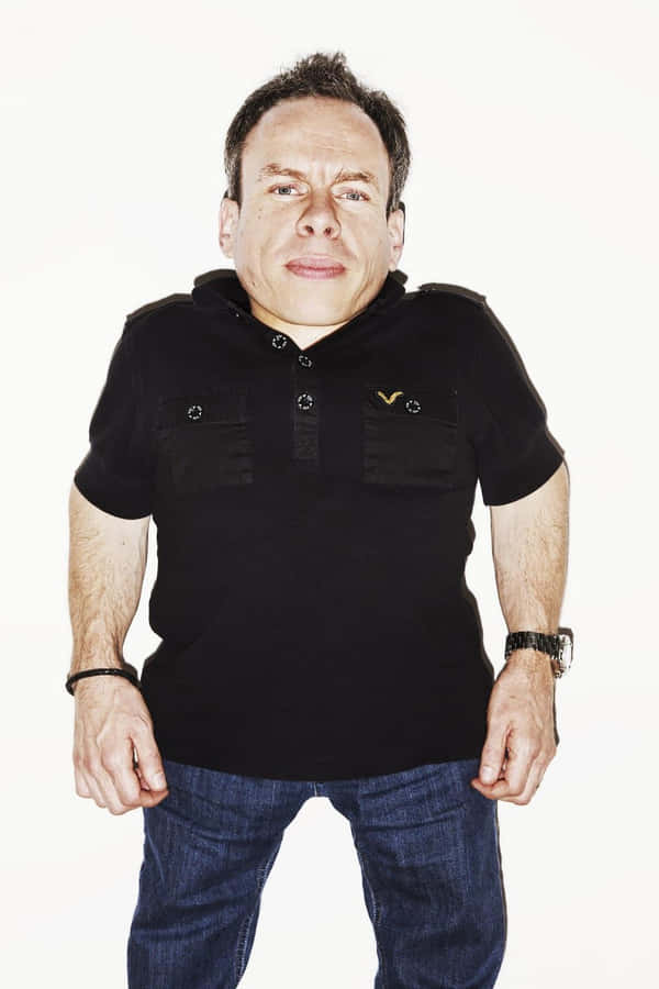 Warwick Davis Posing At An Event Wallpaper