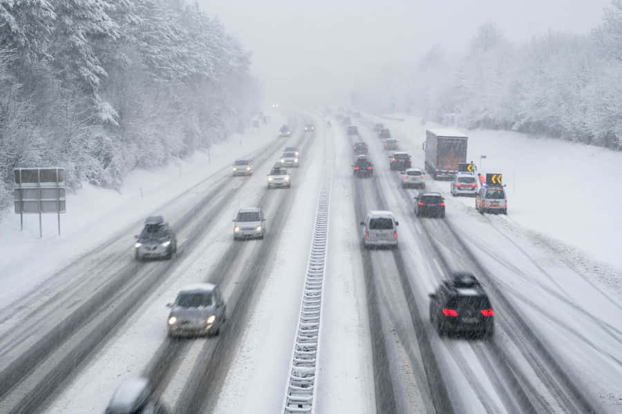 Winter Adventure: A Car Driving On A Snowy Road Wallpaper
