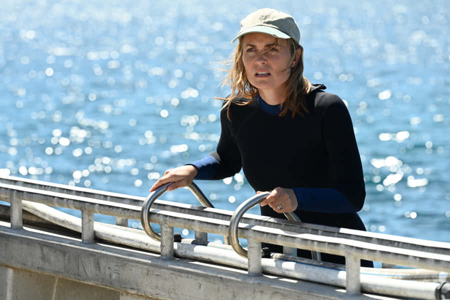 Woman Leaningon Railingby Sea Wallpaper