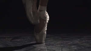 A Ballet Dancer Is Standing On A Dark Floor Wallpaper