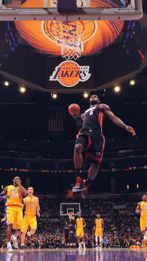 A Basketball Player Is Dunking The Ball In The Air Wallpaper