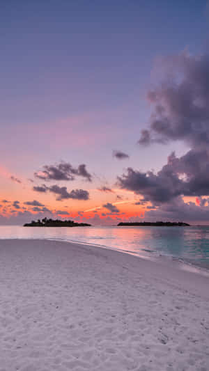 A Beach With Sand And Water At Sunset Wallpaper