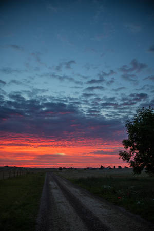 A Beam Of Sunlight Illuminates A Country Road At Sunrise Wallpaper