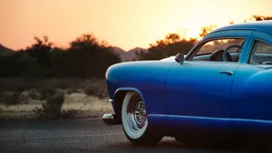 A Beautiful Blue Car Parked In A Chic Neighborhood. Wallpaper