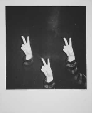 A Black And White Photo Of Three People Making Peace Signs Wallpaper