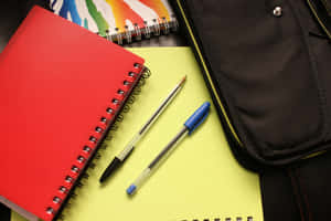 A Black Backpack With A Red Notebook Wallpaper