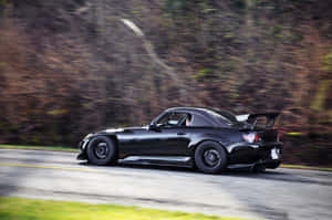 A Black Car Driving Down A Road Wallpaper