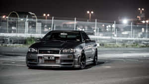 A Black Car Parked In A Parking Lot At Night Wallpaper