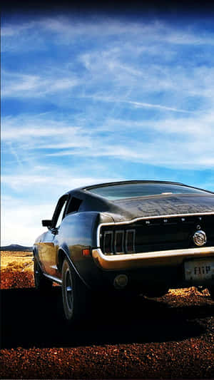 A Black Car Parked On A Dirt Road Wallpaper