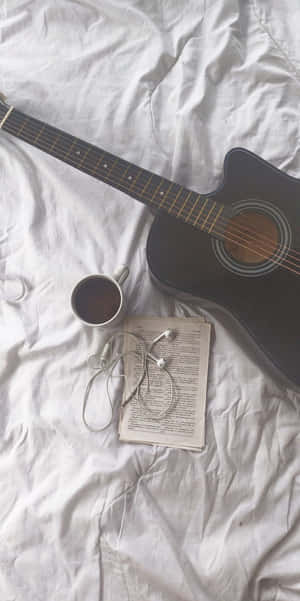 A Black Guitar Laying On Top Of A Beautiful Wooden Board. Wallpaper