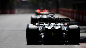 A Black Racing Car Driving Down A Street Wallpaper