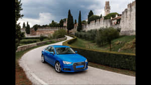 A Blue Audi A4 Driving Down A Road Wallpaper