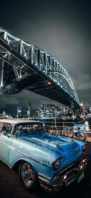 A Blue Car Parked In Front Of A Bridge Wallpaper