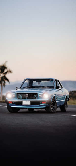 A Blue Mustang Is Driving Down The Road Wallpaper