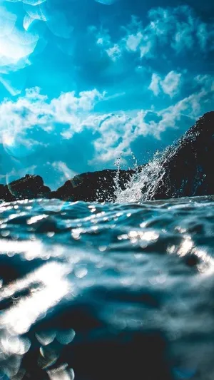 A Blue Sky With Clouds And Water Splashing Wallpaper