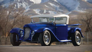 A Blue Vintage Car With Snowy Mountains In The Background Wallpaper