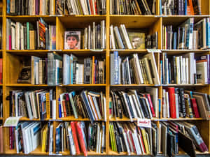 A Book Shelf With Many Books Wallpaper