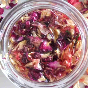 A Bottle Of Fragrant Rose Oil Surrounded By Fresh Rose Petals Wallpaper