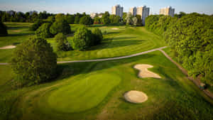 A Breathtaking Golf Course With A Stunning Mountain Backdrop Wallpaper