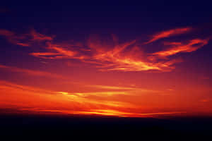 A Breathtaking Red Sunset Over A Calm Sea Wallpaper